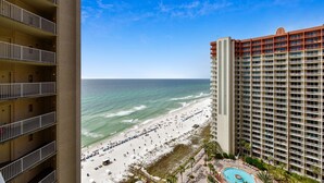 A high-rise hotel with multiple balconies overlooking a beach and ocean.