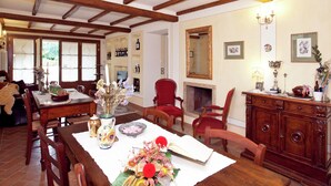Un comedor con vigas de madera, chimenea y una silla roja.