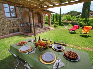 An outdoor dining area with a stone building, a covered patio, and a well-maintained lawn. - Tuscan Style Apartment with View of the Hills (Lucignano)