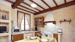 Una cocina acogedora con vigas de madera, una mesa de comedor dispuesta para dos personas y un microondas en la encimera.