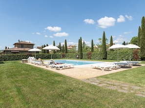 A pool area with lounge chairs, umbrellas, and a stone building in the background. - Tuscan Style Apartment with View of the Hills (Lucignano)
