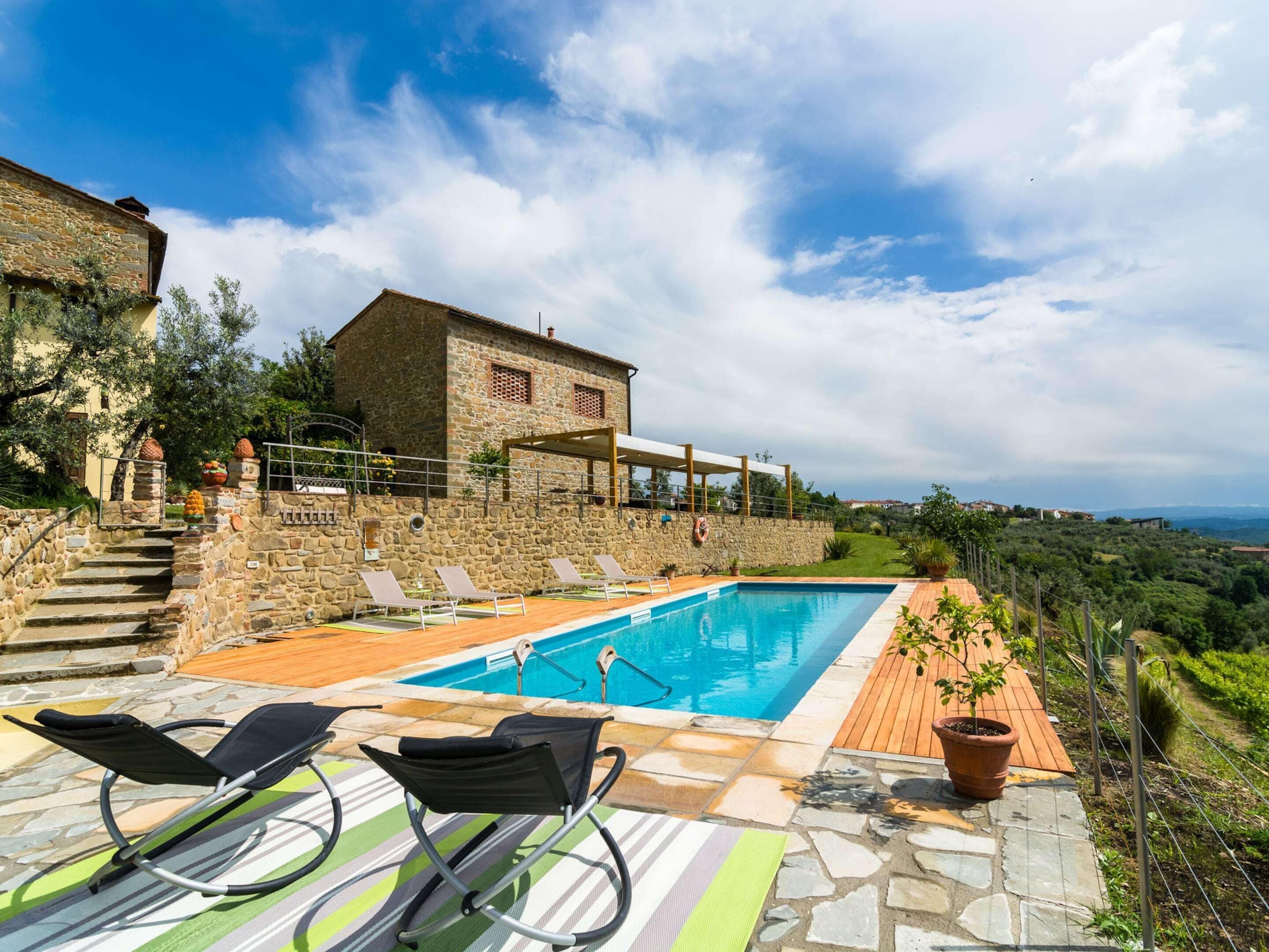 Una villa de piedra con piscina, mobiliario de exterior y vistas al campo.