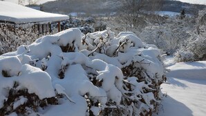 A snowy landscape with a hill in the background and a building with a snow-covered roof. - House With the Pool and Fenced Garden, Great View at Trosky Castle (Ktová)