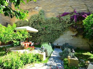 A stone wall with climbing plants and a paved pathway. - Belvilla by OYO Palazzo Pio (Lecce)