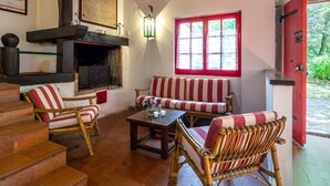 A cozy room with a fireplace, striped sofas, and wicker chairs. - Belvilla by OYO Due Camini (San Marcello Piteglio)