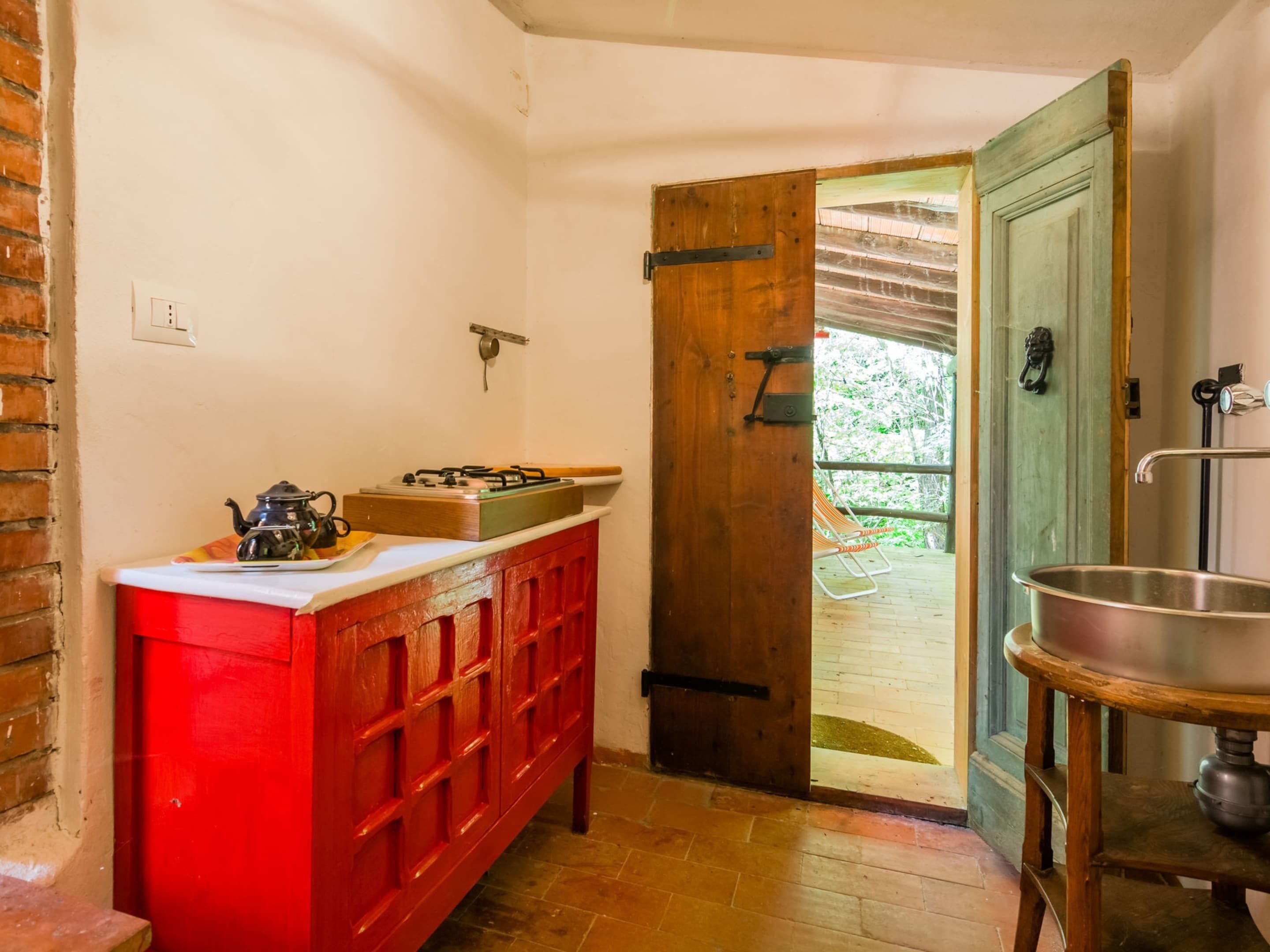 A kitchen with a red cabinet, a gas stove, and a sink.