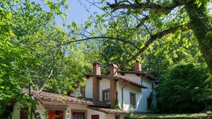 A rustic house with a tiled roof, a red door, and a patio with a table and chairs. - Belvilla by OYO Due Camini (San Marcello Piteglio)
