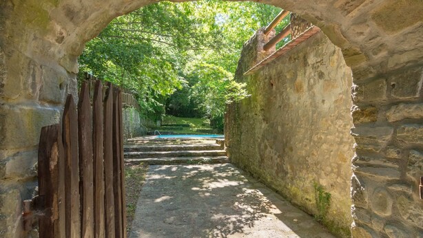 A stone archway leading to a pool area with steps and a wooden fence. - Belvilla by OYO Due Camini (San Marcello Piteglio)