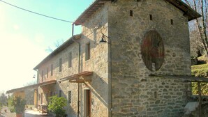 Un bâtiment en pierre avec une porte et des fenêtres en bois, entouré de gravier et de plantes en pot.