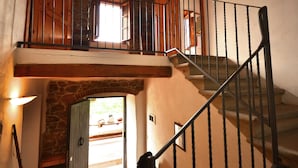 Un escalier surmonté d’une arche en pierre menant à un balcon du deuxième étage.