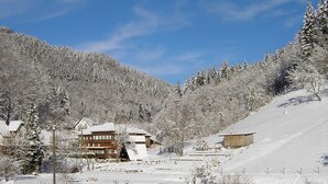 A snow-covered mountain area with several buildings, including a large lodge with multiple windows and a sloped roof. - Comfy Apartment in Oppenau near Black Forest National Park (Oppenau)