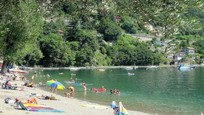 A beach with people sunbathing, swimming, and playing in the water. - Appartamento in Centro Storico a Cannero Riviera (Cannero Riviera)