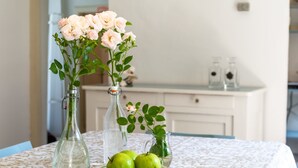 A table with three glass vases, one containing pink roses and the other two with green leaves, and a plate with three green apples. - Appartamento in Centro Storico a Cannero Riviera (Cannero Riviera)