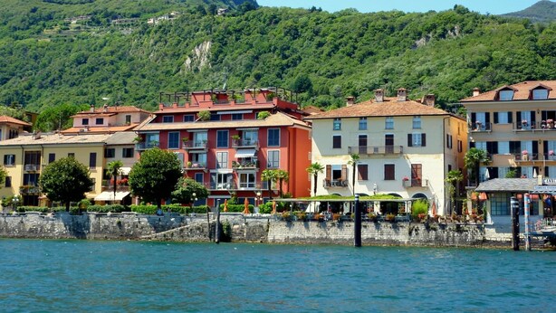 A waterfront hotel with multiple floors, balconies, and a stone wall along the water. - Appartamento in Centro Storico a Cannero Riviera (Cannero Riviera)