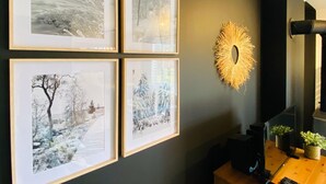 Un mur orné de quatre photographies en noir et blanc encadrées, représentant des paysages d’hiver.