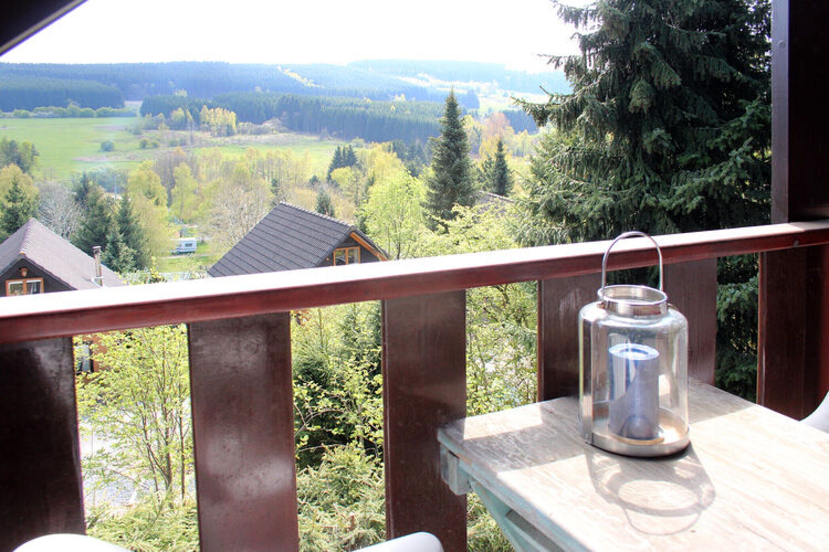 Un balcón con vista a un bosque y casas.