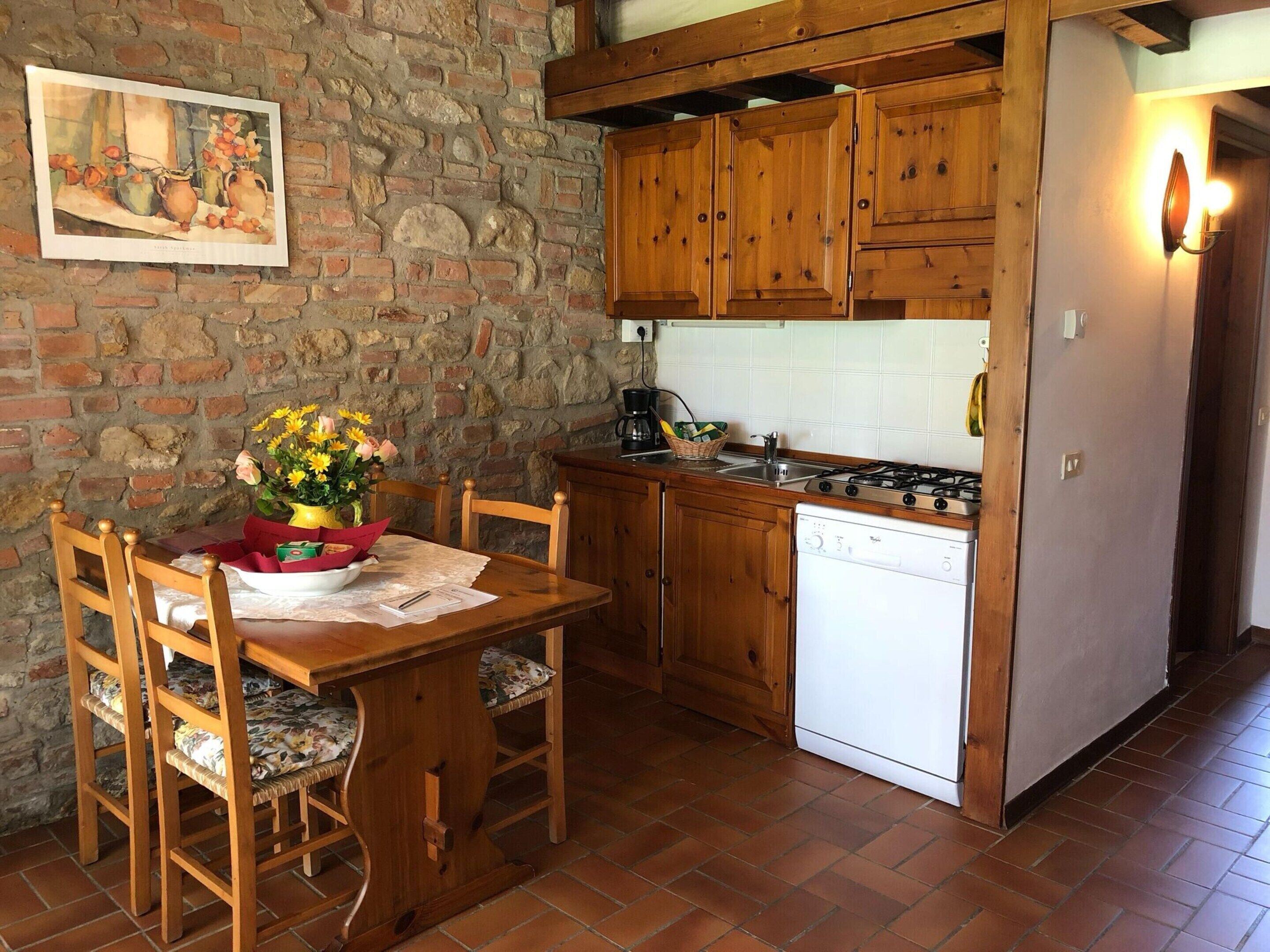 A rustic kitchen with wooden cabinets, a white dishwasher, and a dining table with chairs.