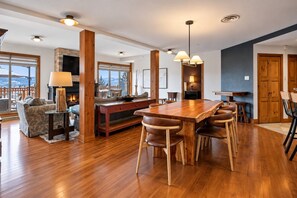 A spacious living area with a wooden dining table, comfortable seating, a fireplace, and large windows offering a view. - Tremblant Prestige - Altitude 170-2 (Mont-Tremblant)