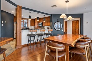 A modern kitchen with wooden cabinets, a central island with bar stools, and pendant lighting. - Tremblant Prestige - Altitude 170-2 (Mont-Tremblant)
