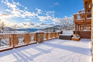 A snow-covered deck with a hot tub, wooden railing, and a stone pillar. - Tremblant Prestige - Altitude 170-2 (Mont-Tremblant)