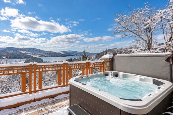 A hot tub on a balcony with a snowy landscape and mountains in the background.