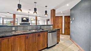 A modern kitchen with granite countertops, wooden cabinets, and a stainless steel dishwasher. - Tremblant Prestige - Altitude 170-2 (Mont-Tremblant)