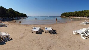 A beach with white lounge chairs and a sandy shore. - Holiday Home Near Vrana Lake and Adriatic Sea (Benkovac)
