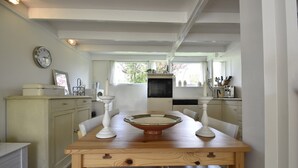 A kitchen with a wooden table, white cabinets, and a clock on the wall.