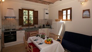 Cocina compacta con estufa a gas, horno y comedor con mesa para dos.