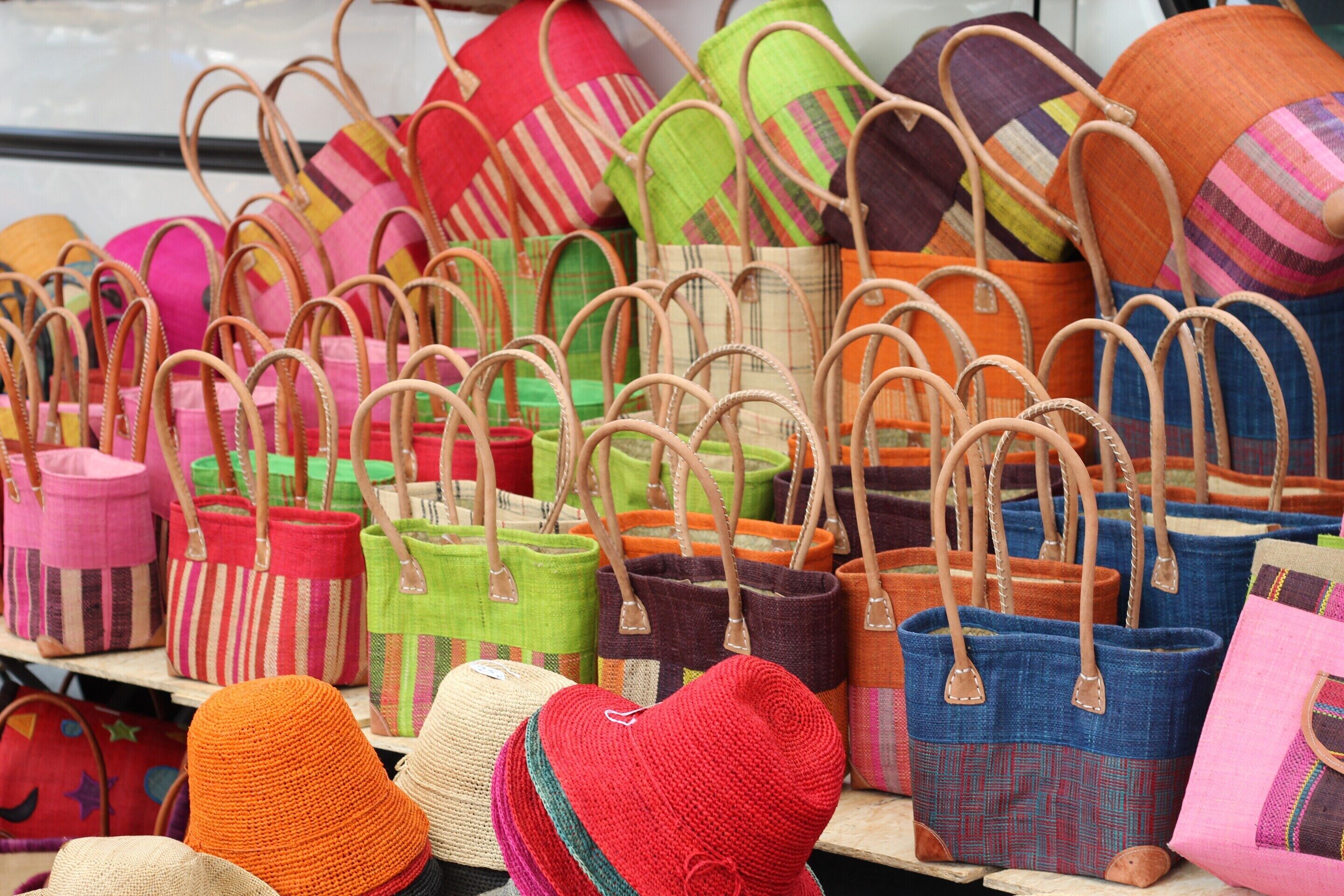 A variety of colorful woven bags displayed on a shelf.
