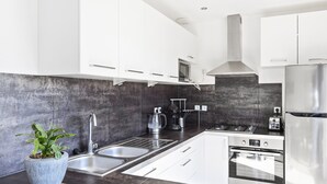 A modern kitchen with white cabinets, stainless steel appliances, a large sink, and a potted plant. - Holiday Home in Brignoles With Private Pool (Brignoles)