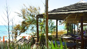 A beachside restaurant with outdoor seating, a thatched roof, and views of the sea. - House in Tuscany Near Baratti Beach (Campiglia Marittima)