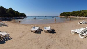 Una playa con sillas de descanso blancas y una orilla arenosa.