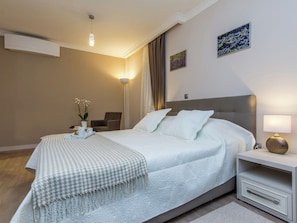 Een netjes ingerichte slaapkamer met een bed, nachtkastje, lamp en decoratieve wandkunst.