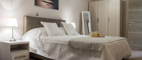 A neatly arranged bedroom with a bed, bedside table, and a nightstand.