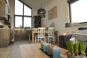 A modern kitchen with stainless steel appliances, a dining area with white chairs, and a large window providing natural light. - Lovely Holiday Home in Stavoren near Frisian Lakes (Stavoren)