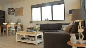 Uma sala de estar moderna com sofá, mesa de centro e área de jantar.