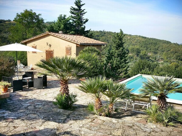 Ein Haus mit Pool, Gartenmöbeln und Palmen.