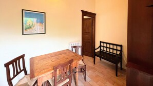 A dining area with a wooden table and chairs, a bench, a framed picture on the wall, and a door. - Farmhouse in Giano Dell'umbria with Hot Tub, Swimming Pool (Giano dell'Umbria)