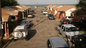A row of single-story buildings with a paved driveway. - Bayfront Cottage Room 16 (Rockport)