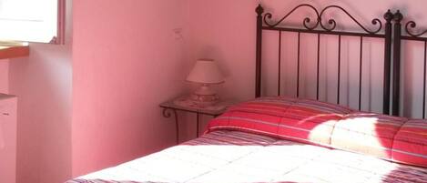 A bedroom with a bed, a nightstand, a lamp, and two framed pictures on the wall.