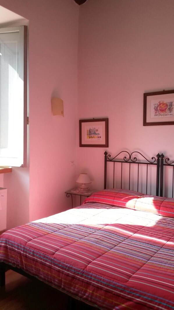 A bedroom with a bed, a nightstand, a lamp, and two framed pictures on the wall.