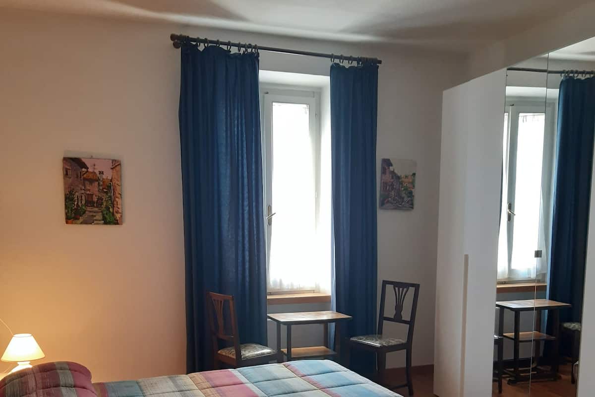 Une chambre à coucher avec un lit, un bureau, des chaises et une fenêtre avec des rideaux.