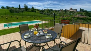 A terrace with a pool, outdoor seating, and a view of a village.