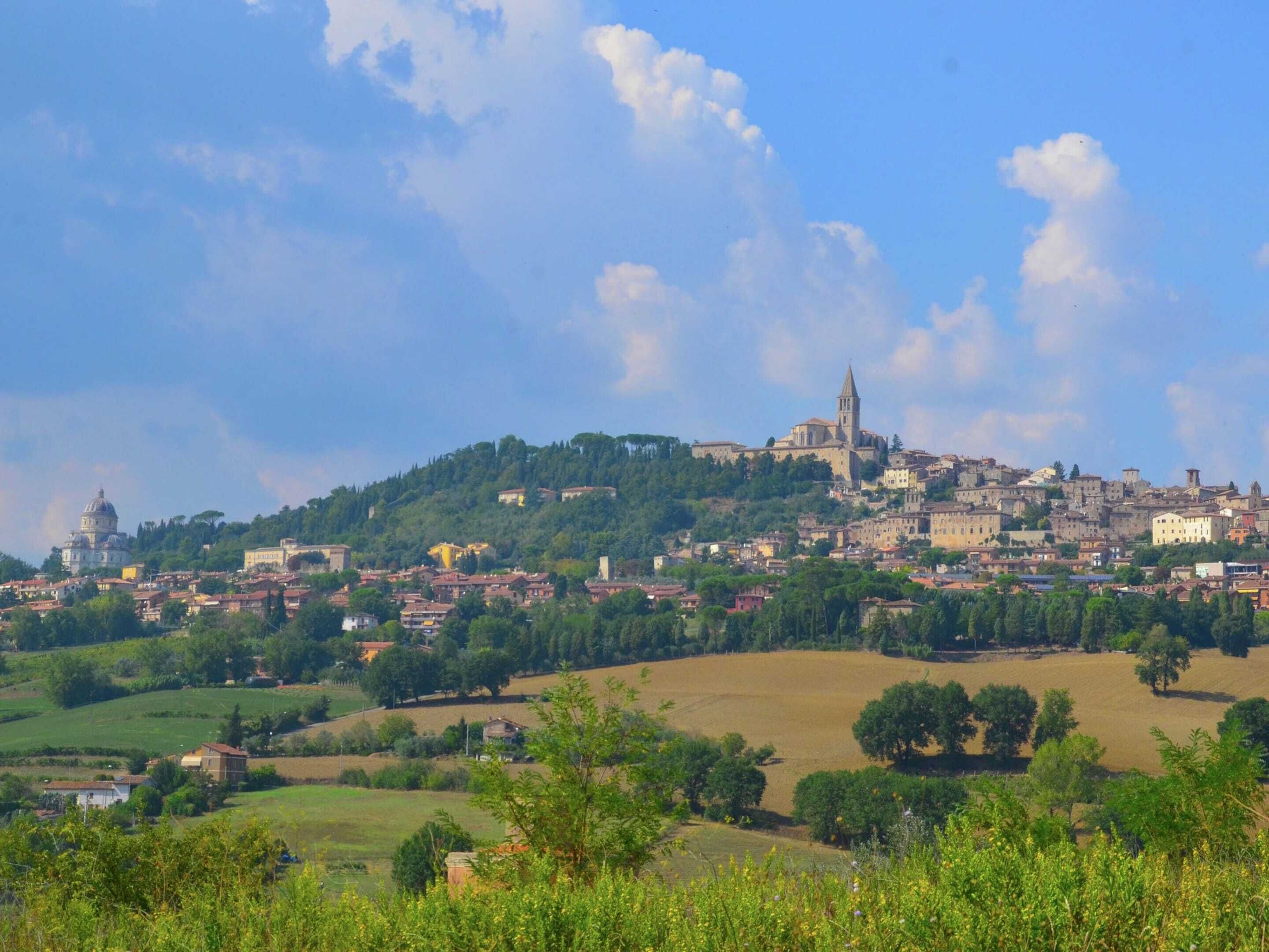 A historic town with a prominent church on a hill, surrounded by lush greenery and rolling hills.
