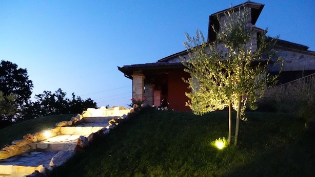 A stone staircase leading to a building with a red facade and a tree illuminated by a spotlight.
