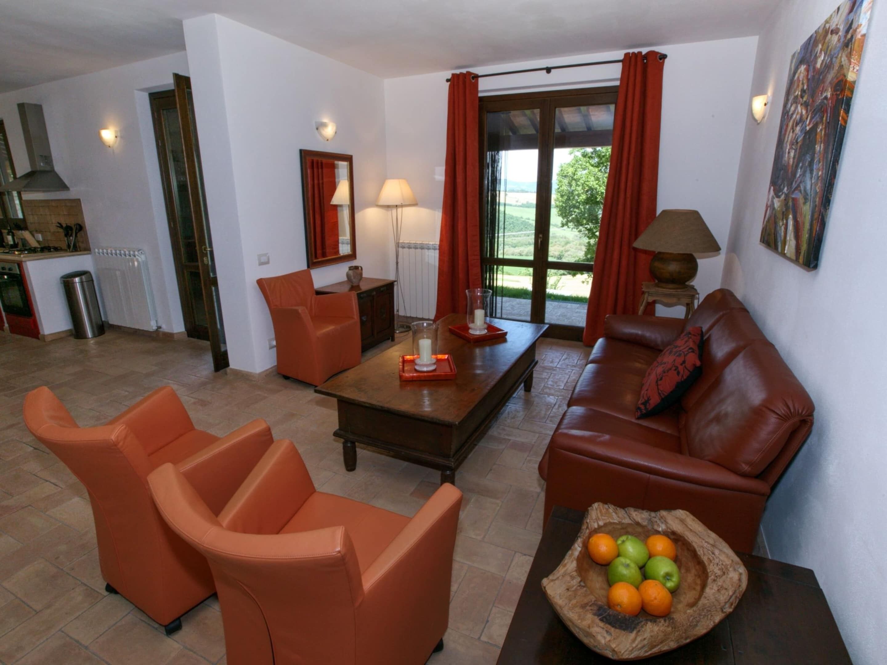 Ein Wohnzimmer mit orangefarbenen Möbeln, einem Couchtisch und einer Obstschale.