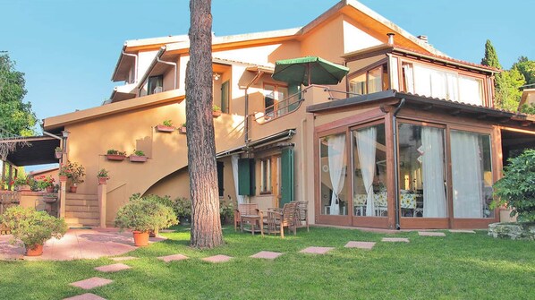 Una casa a due piani con un balcone, un portico coperto e un prato.