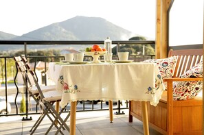 A table set for breakfast on a balcony with a mountain view.