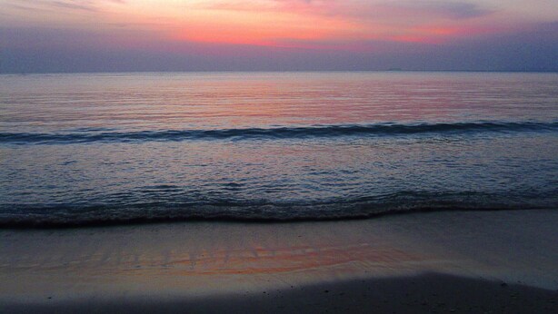 Una playa con olas y un atardecer.